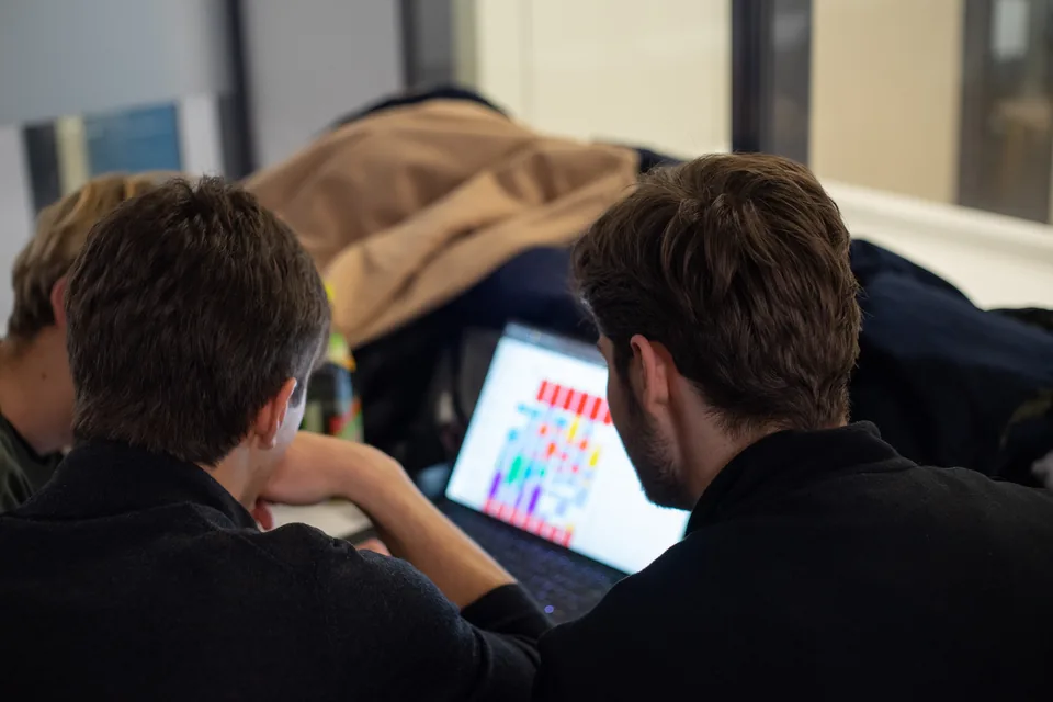 Enactus Munich members viewing a shared laptop screen during a Celonis workshop