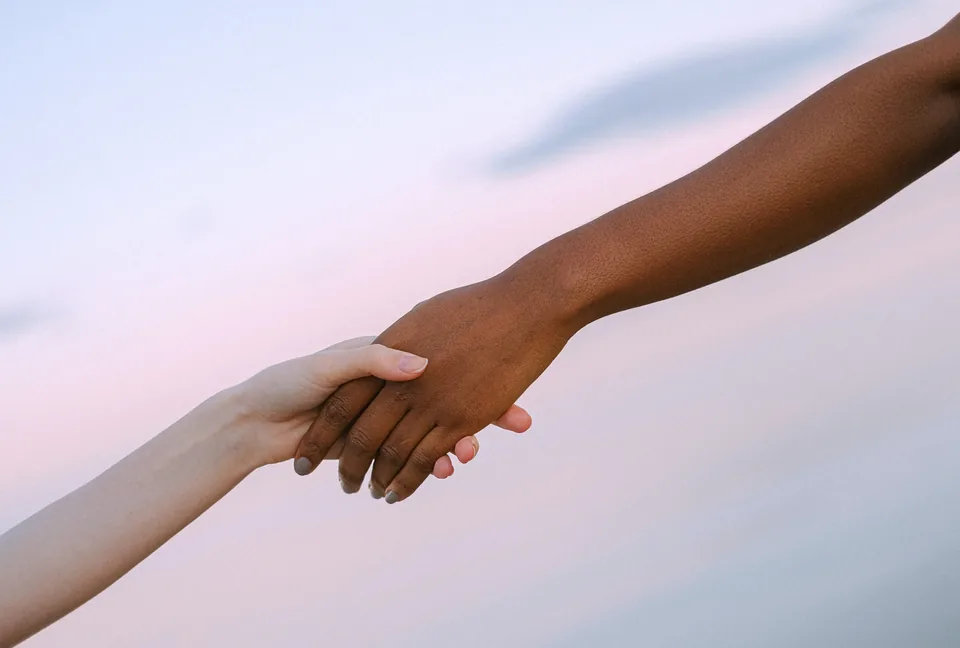 Two people holding hands in support of one another